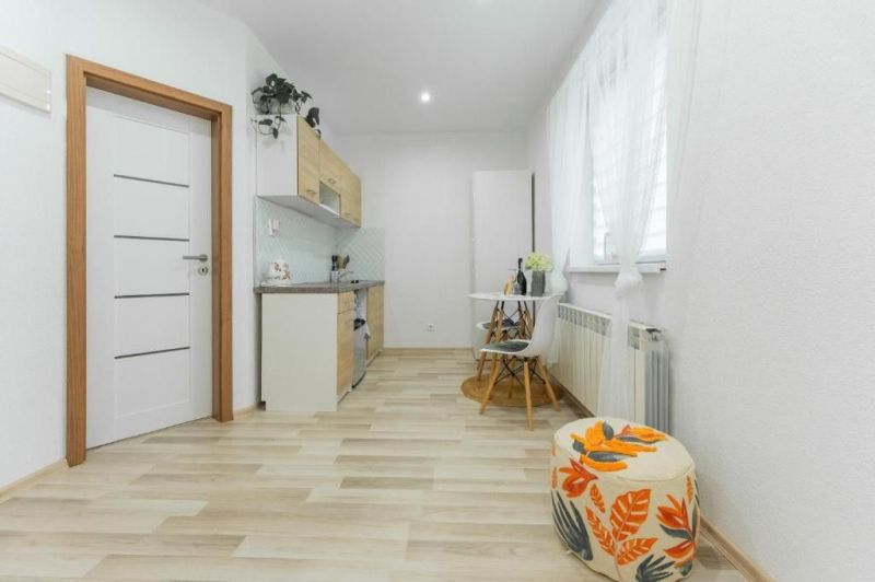Moderný apartmán v centre Rajeckých Teplíc rovno oproti kúpeľom Afrodi - Svetlá kuchyňa v Rekreačnom apartmáne s podlahou s dreveným dekorom a jednoduchým nábytkom.