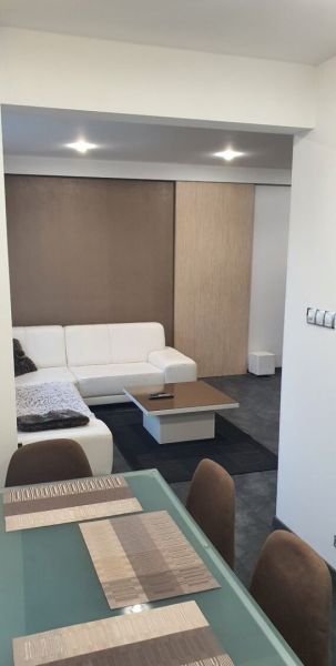 Nadštandardný, dômyselne zariadený 3-izbový byt  - PREDAJ. - Obývacia izba 3-izbového bytu s bielou sedačkou a stolom na prestieranie.