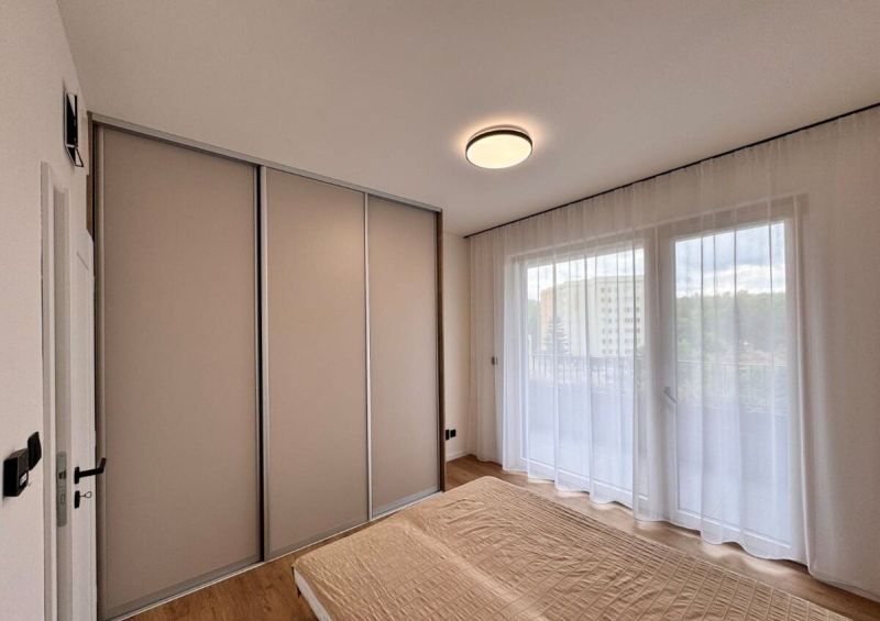 Prenájom nový 2-izbový byt -49m² Žilina-Vlčince, EUROTERRACE - Spálňa v 2-izbovom byte s posteľou, posuvnými dverami a závesmi na okne.