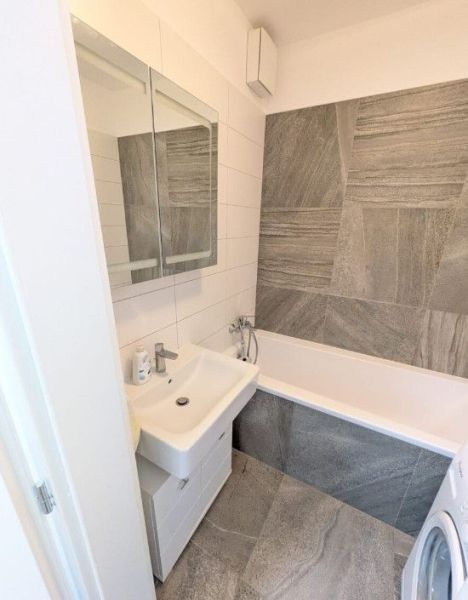 Moderný 2-izbový byt s balkónom a výhľadom - Kúpeľňa v 2-izbovom byte s umývadlom, vaňou a svetlými obkladmi.