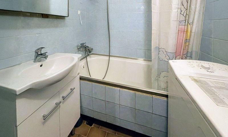 Predaj: Priestranný 3-izbový Byt s Balkónom a Potenciálom na Východe! - Kúpeľňa s bielou vaňou, umývadlom a práčkou v 3-izbovom byte.
