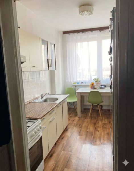 Predaj 3-izbový byt s loggiou a šatníkom – Kyjevská ul., Michalovce - Kuchyňa v 3-izbovom byte s bielymi skrinkami a podlahou s dreveným dekorom.