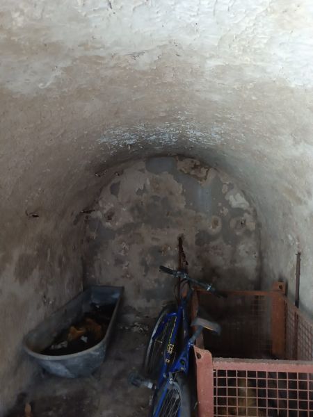 Na predaj chalupa  Banská Hodruša v tichej lokalite - Na obrázku je klenbová miestnosť s bicyklom, starým vybavením, pripomínajúca pivničný priestor.