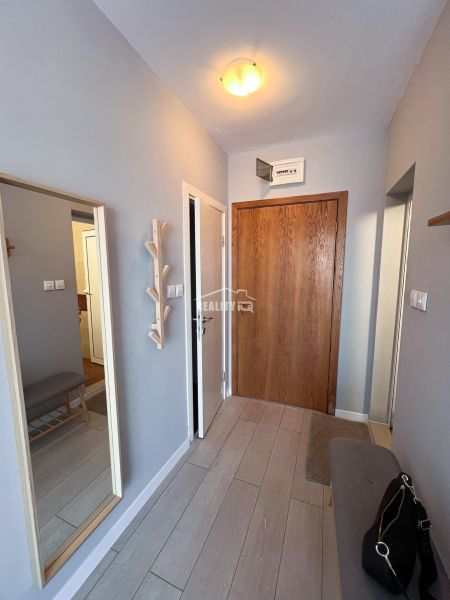 Moderná garsónka (41 m²) s výhľadom na bazén – Rezort ANTARES - Garsónka so zrkadlom, drevenou lavičkou a podlahou s dreveným dekorom.