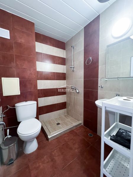 Moderná garsónka (41 m²) s výhľadom na bazén – Rezort ANTARES - Kúpeľňa s bezbariérovým sprchovým kútom, hnedými a béžovými obkladačkami v garsónke.