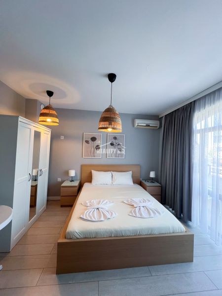 Moderná garsónka (41 m²) s výhľadom na bazén – Rezort ANTARES - Garsónka s manželskou posteľou, skriňou a nočnými stolíkmi, dekor dreveného nábytku.