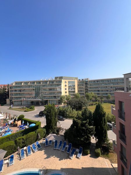 Moderná garsónka (41 m²) s výhľadom na bazén – Rezort ANTARES - Výhľad na apartmány a bazén v Slnečnom pobreží, kreslá a slnečníky.