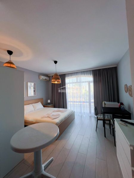 Moderná garsónka (41 m²) s výhľadom na bazén – Rezort ANTARES - Garsónka s manželskou posteľou, stolom a stoličkami, podlaha s dreveným dekorom.