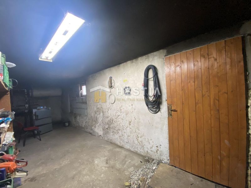 NA PREDAJ 6-IZB. RODINNÝ DOM, Senica – Čáčov - Garáž rodinného domu s drevenými dverami, regálmi a osvetlením, v obci Senica.