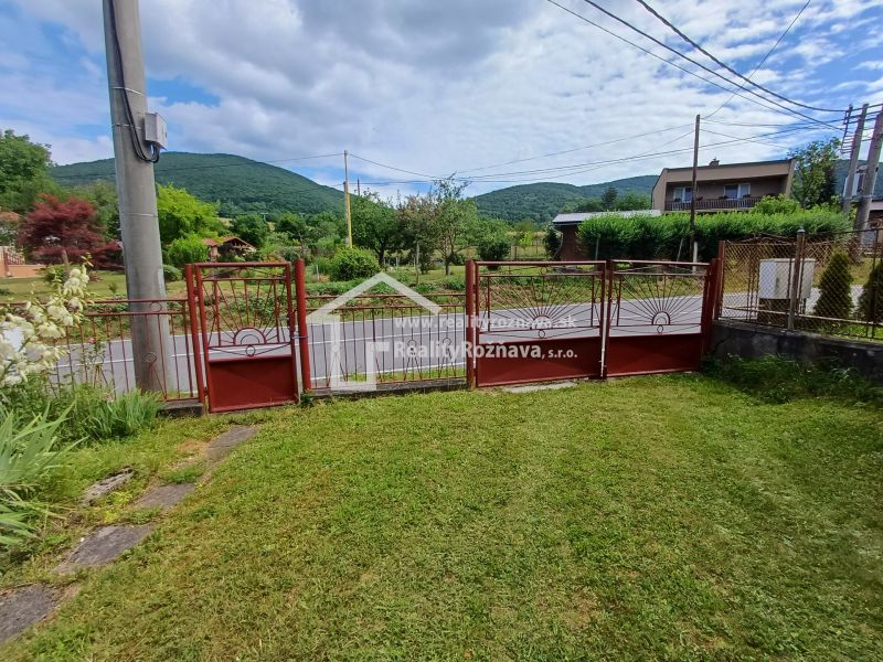 Pekný rodinný s nádherným výhladom. - Garážová brána rodinného domu v Rožňavskom Bystrom obklopená záhradou a panorámou kopcov.
