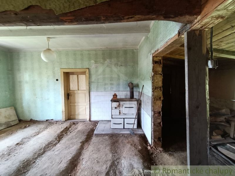 Pozemok s drevenicou na Kysuciach s krásnym výhľadom, Olešná - Staršia chata s kozubom a odkrytou podlahou s hlineným povrchom.