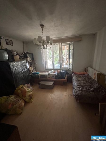 Na predaj starší rodinný dom v obci Budmerice 541m2 - Izba v rodinnom dome s posteľou, televízorom, lustrom a káblovou neporiadkou.