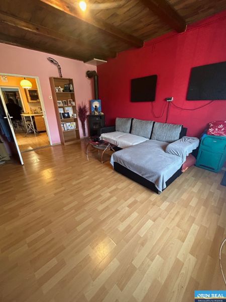 Na predaj starší rodinný dom v obci Budmerice 541m2 - Obývacia izba v rodinnom dome so sedačkou, krbom a dreveným stropom.