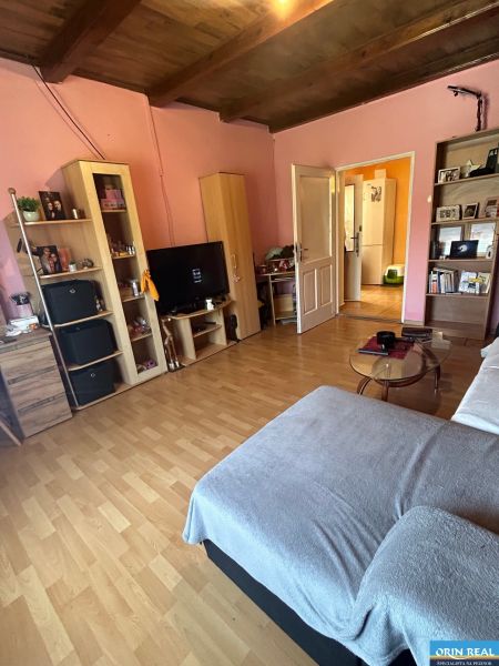 Na predaj starší rodinný dom v obci Budmerice 541m2 - Obývacia izba rodinného domu s dreveným stropom, rúžovými stenami, pohovkou a nábytkom.
