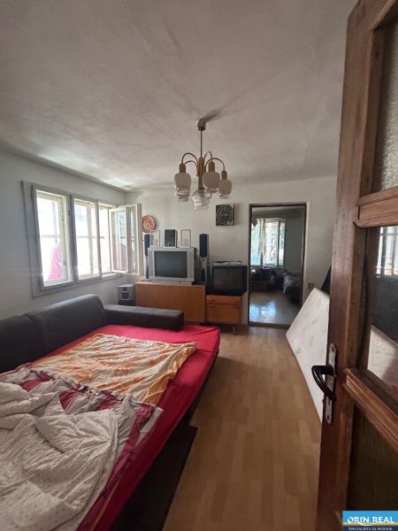 Na predaj starší rodinný dom v obci Budmerice 541m2 - Obývacia izba v rodinnom dome s rozkladacou pohovkou, televízormi a lustrom.