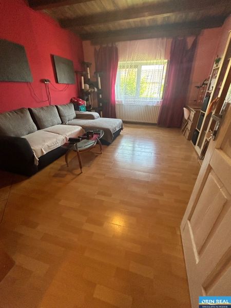 Na predaj starší rodinný dom v obci Budmerice 541m2 - Obývacia izba s dreveným stropom, pohovkou a oknom so záclonou v rodinnom dome.
