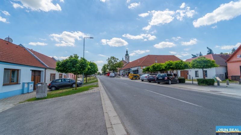 Častá RD s čiastočnou rekonštrukciou a veľkým pozemkom 2934m2 - Ulica Hlavná v Častej s rodinnými domami a zaparkovanými autami.