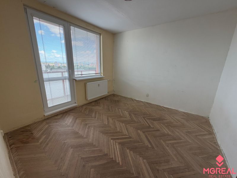 2 izbový byt s 2 balkónmi Topoľčany / VYPLATENA ZALOHA - Izba v 2-izbovom byte s balkónom a podlahou s dreveným dekorom.