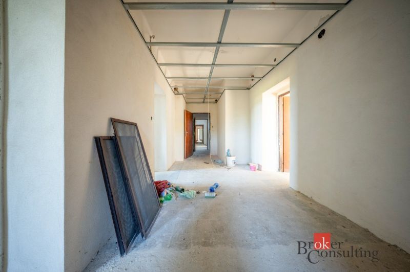 Na predaj budova na bývanie alebo podnikanie, Kalonda - Prázdna chodba rodinného domu s rozloženými materiálmi a prípravkami na podlahe.