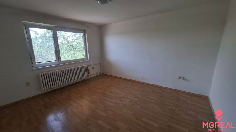 4. izb. RD Čakajovce pri Nitre  - Prázdna izba so stenami bielej farby a podlahou s dreveným dekorom v rodinnom dome.