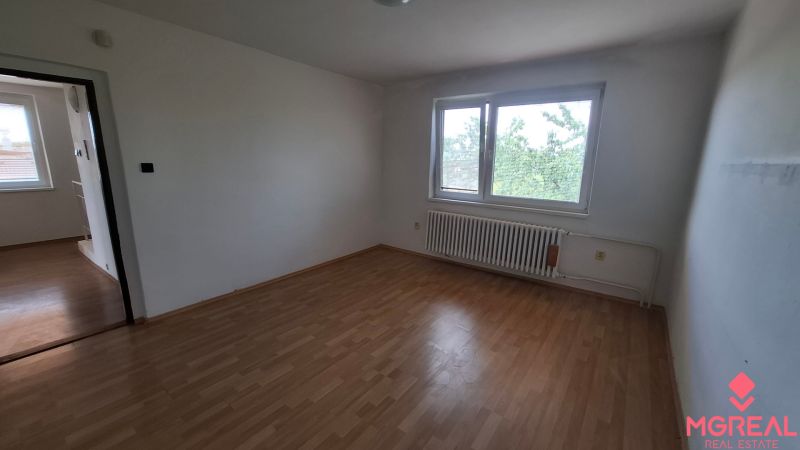 4. izb. RD Čakajovce pri Nitre  - Izba s bielymi stenami, podlaha s dreveným dekorom, veľké okno a radiátor.