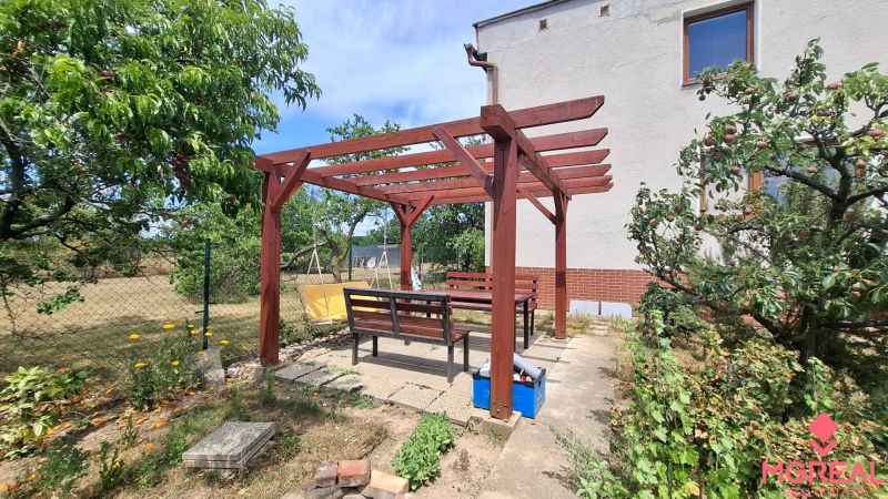 4. izb. RD Čakajovce pri Nitre  - Pergola a lavičky v záhrade rodinného domu v Čakajovciach obklopené ovocnými stromami.