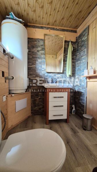 PRIESTRANNÝ DREVODOM S NÁDHERNÝM VÝHĽADOM, ĽUBIETOVÁ,  POZEMOK 2781 M2 - Kúpeľňa v rodinnom dome so zrkadlom, skrinkou a ohřívačom vody, drevené obloženie.
