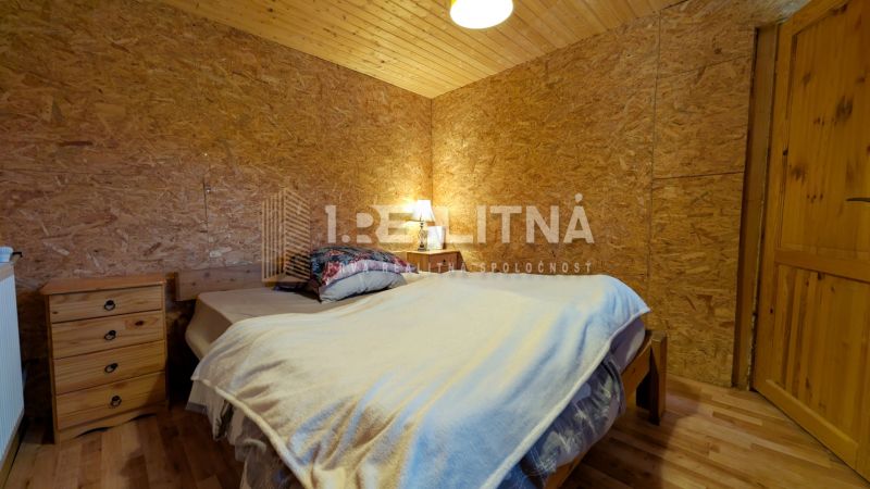 PRIESTRANNÝ DREVODOM S NÁDHERNÝM VÝHĽADOM, ĽUBIETOVÁ,  POZEMOK 2781 M2 - Spálňa v Rodinnom dome s drevenými stenami a pohodlnou posteľou.