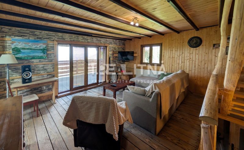 PRIESTRANNÝ DREVODOM S NÁDHERNÝM VÝHĽADOM, ĽUBIETOVÁ,  POZEMOK 2781 M2 - Drevený interiér obývačky s pohovkou a televíziou v Rodinnom dome.