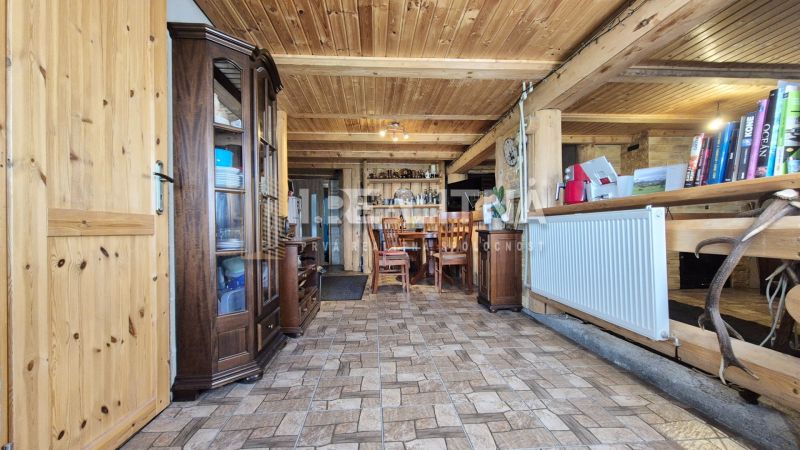 PRIESTRANNÝ DREVODOM S NÁDHERNÝM VÝHĽADOM, ĽUBIETOVÁ,  POZEMOK 2781 M2 - Interiér rodinného domu s dreveným stropom, skrinkami a stolom s drevenými stoličkami.