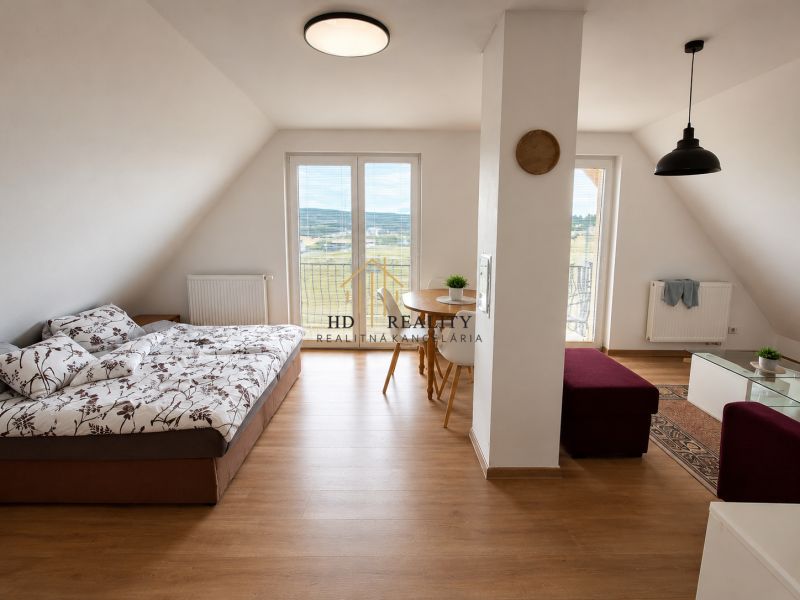 Prenájom, Apartmán v meste Krupina - Svetlá izba s podlahou s dreveným dekorom, sedačkou a jedálenským stolom v 2-izbovom byte.