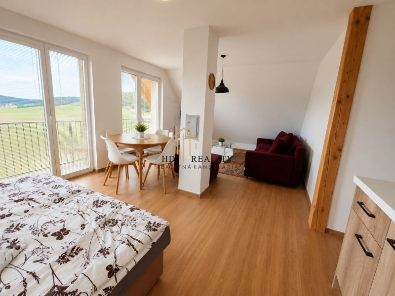 Prenájom, Apartmán v meste Krupina - Interiér 2-izbového bytu s posteľou, stolom a podlahou s dreveným dekorom.