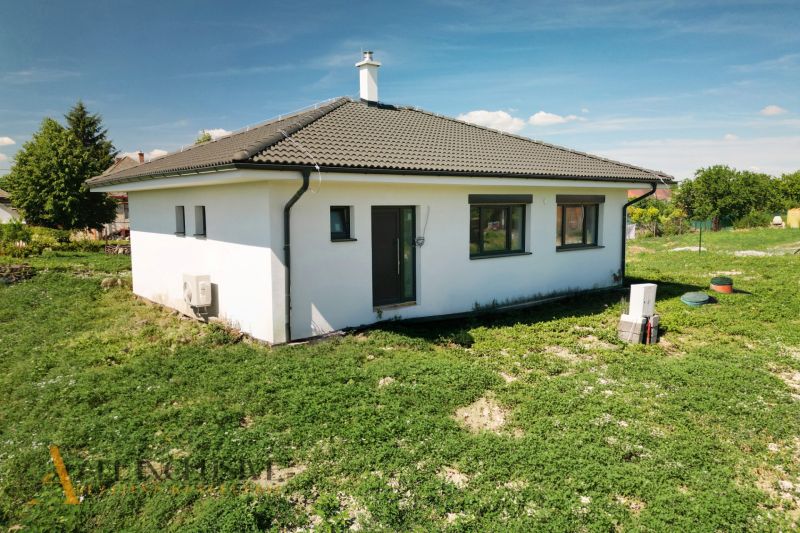 Projekt ČEREŠŇOVÁ ALEJ – 10 rod. domov/pozemk., Jelka - Rodinný dom v Jelke s bielou fasádou a šikmou strechou na zelenej záhrade.