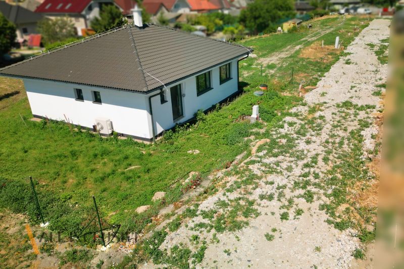 Projekt ČEREŠŇOVÁ ALEJ – 10 rod. domov/pozemk., Jelka - Rodinný dom v Jelke s trávnatou záhradou a šikmou strechou.
