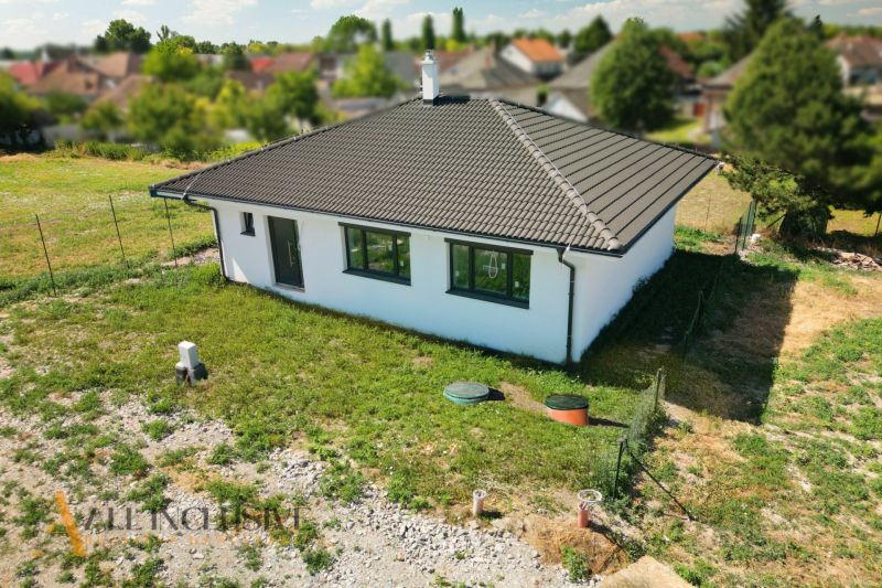 Projekt ČEREŠŇOVÁ ALEJ – 10 rod. domov/pozemk., Jelka - Rodinný dom v Jelke s úhľadnou fasádou a sedlovou strechou, obklopený záhradou.