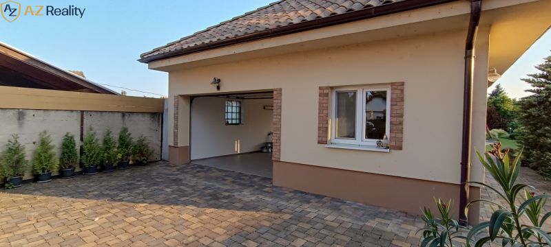 NA PREDAJ – DOM, KDE KAŽDÝ DEŇ JE DOVOLENKA - Garáž rodinného domu v Palárikove so zámkovou dlažbou a malými tujami.