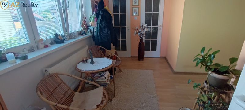 NA PREDAJ – DOM, KDE KAŽDÝ DEŇ JE DOVOLENKA - Kútik v rodinnom dome s ratanovým nábytkom a dekoráciami na parapete.