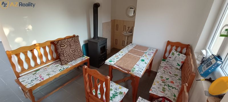 NA PREDAJ – DOM, KDE KAŽDÝ DEŇ JE DOVOLENKA - Interiér rodinného domu s lavičkami, stolom a pieckou, doplnený vzorovanými poduškami.