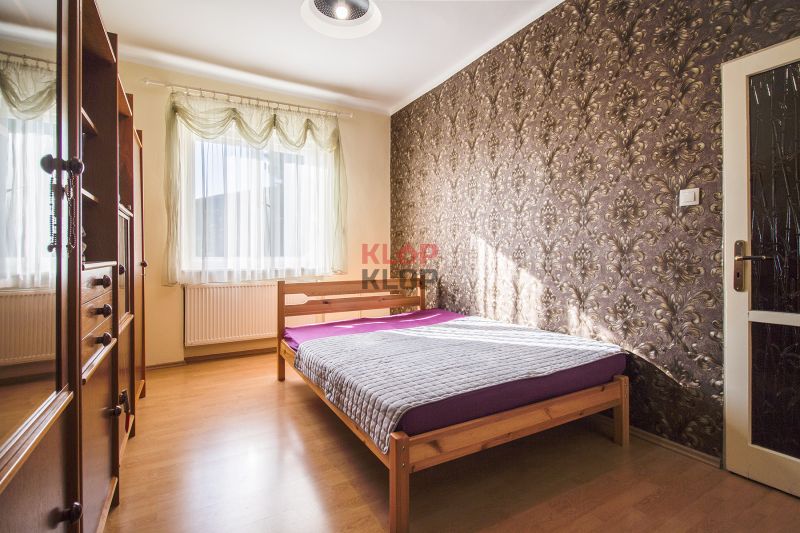 Kúpte si PÔVABNÝ 4i RD na SKVELOM POZEMKU s GARÁŽOU a HALAOU - Spálňa s drevenou posteľou a tapetou, svetlo prechádza cez záclony v rodinnom dome.
