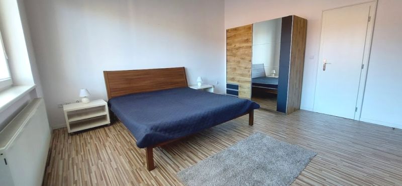 PRENÁJOM: VEĽKOMETRÁŽNY 2 IZBOVÝ BYT S 2 LOGGIAMI, CENTRUM - Spálňa v 2-izbovom byte s posteľou, skriňou a podlahou s dreveným dekorom.