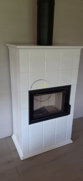 Výnimočná zrubová chata na predaj, Čechy, okr. Nové Zámky - Kachľová pec v chate na podlahe s dreveným dekorom.