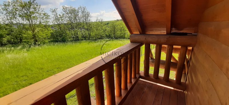 Výnimočná zrubová chata na predaj, Čechy, okr. Nové Zámky - Balkón chaty s výhľadom na zelenú lúku a lesné stromy v Čechách.