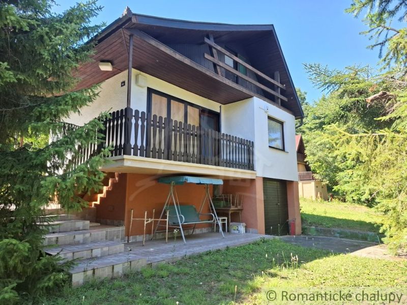 Poschodová chata pri lese blízko Dunaja v rekreačnej oblasti Kováčovsk - Chata v Chľabe obklopená stromami s terasou a posedením.