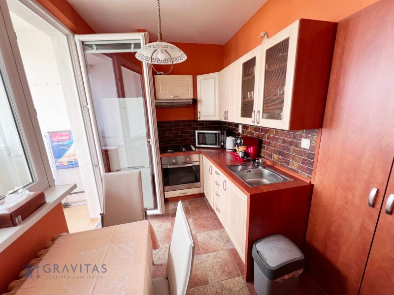 Na prenájom zariadený 2 izbový byt, Dlhé diely - Kuchyňa v 2-izbovom byte s oranžovými stenami, keramickou dlažbou a vstupom na balkón.
