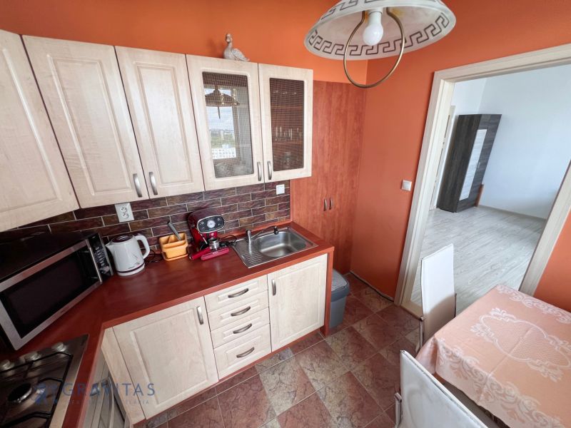 Na prenájom zariadený 2 izbový byt, Dlhé diely - Kuchyňa v 2-izbovom byte s orieškovo-dekorovanými skrinkami a oranžovými stenami.