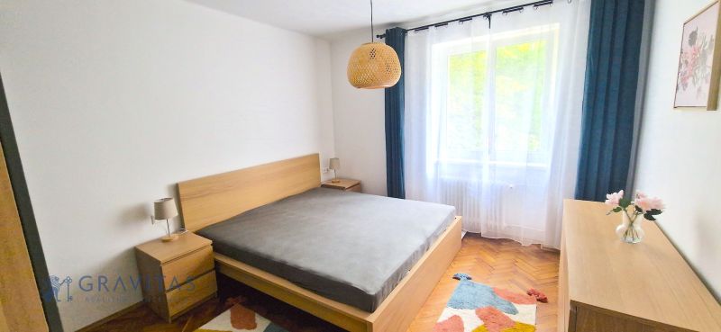 Prenájom 2 izb. bytu Račianske mýto, Bratislava - Spálňa v 2-izbovom byte s podlahou s dreveným dekorom a jednoduchým nábytkom.