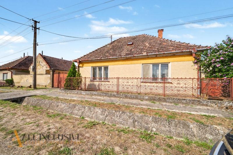 Na predaj 5-izbový rodinný dom, Čierna Voda - Rodinný dom na ulici Čierna Voda v Galante, s výraznou červenou bránou a plotom.