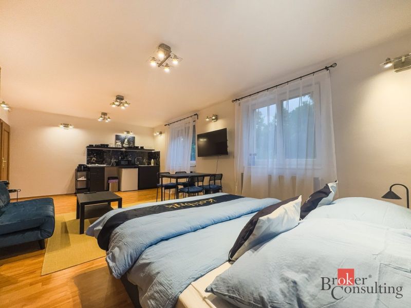 Zariadený 1i apartmán s balkónom na Hradnom kopci - Priestranný 1-izbový byt s podlahou s dreveným dekorom, dvojposteľou a kuchynským kútom.