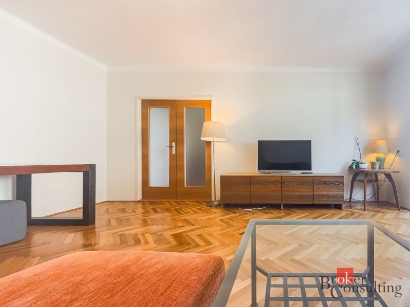Staromestský 2i byt s balkónom na Palisádach - Obývacia izba v 2-izbovom byte s podlahou s dreveným dekorom a televízorom.