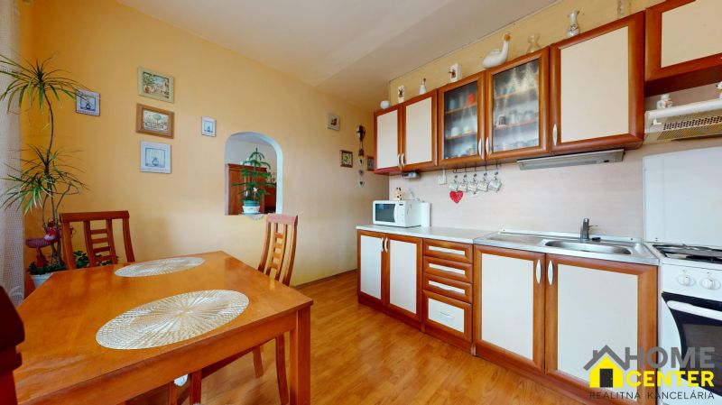 NA PREDAJ 3 IZBOVÝ BYT NA ZAČIATKU VII. SÍDLISKA, UL. PALATÍNOVA - Kuchyňa v 3-izbovom byte so stolom, stoličkami a podlahou s dreveným dekorom.